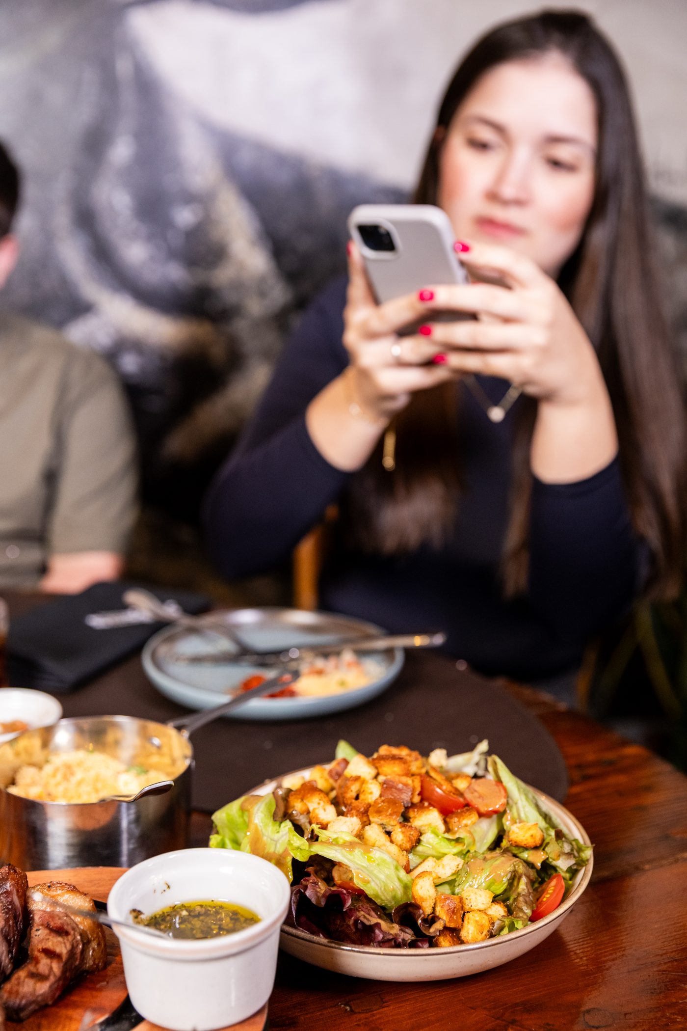 Cliente fotografando a mesa, salada da casa em primeiro plano